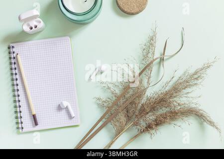 Flat lay still life aroma candle, pampas grass, notepad and pencil on a pastel green background. Mockup, photos with a neutral color palette Stock Photo