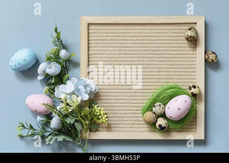 Springtime welcome concept. Letter board, Easter eggs and spring flowers on a pastel blue background, minimalism style composition. View from above Stock Photo