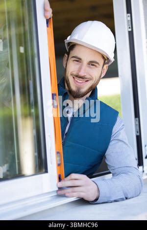 construction worker using bubble level while installing window indoors Stock Photo