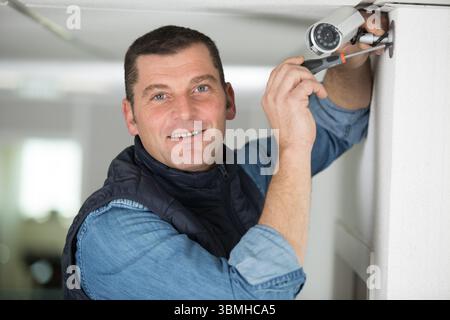 mature technician installing a security camera Stock Photo