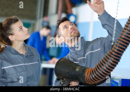 service man and female apprentice checking a ventilation tube Stock Photo