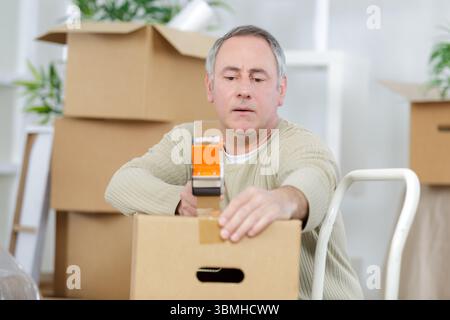 mature man using duct tape for packing stuff in box Stock Photo