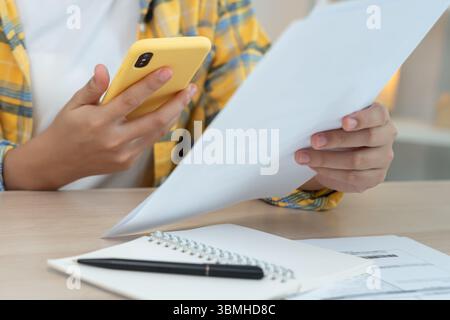 woman use phone scan barcode or QR codes to pay credit card bill after receiving document invoice. payment, receive, paying electricity, digital payme Stock Photo