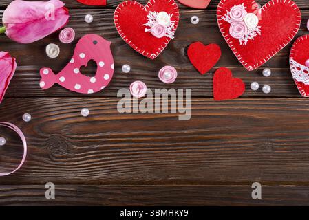 Sewed handmade fabric hearts tulips and ribbon for valentine day on dark wooden background with copy space Stock Photo