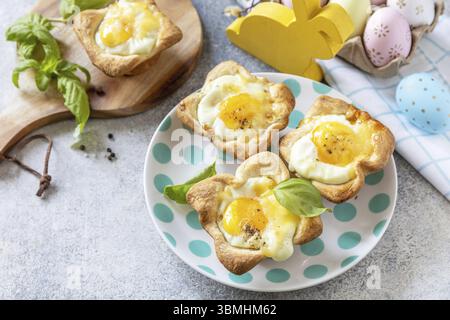 Easter breakfast idea. Scrambled eggs in puff pastry with cheese and bacon on a stone background. Copy space Stock Photo