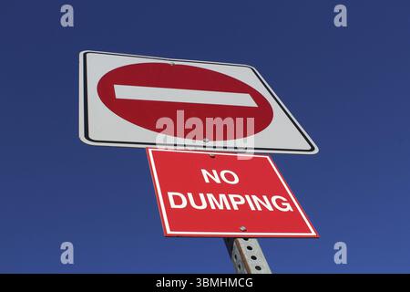 No Entry or Dumping Sign Against Blue Sky Stock Photo