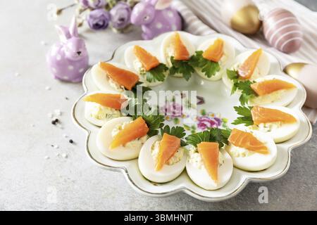 Festive dinner, Easter brunch. Stuffed eggs with cheese and salted salmon in the form of a carrot. Copy space Stock Photo