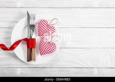 Valentine handmade fabric hearts in plate for romantic dinner flat lay with copy-space background on white wooden table Stock Photo
