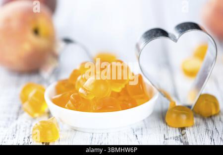 Heap of gummy Peaches on wooden background (close-up shot) Stock Photo
