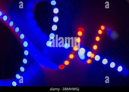 Red and blue blurry neon spirals of bokeh lights on black. Abstract background of 80s colors Stock Photo
