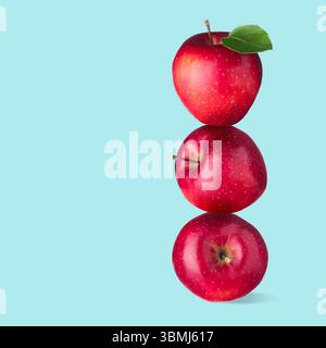 Red apples stacked on top of each other against light blue background. Balance Stock Photo