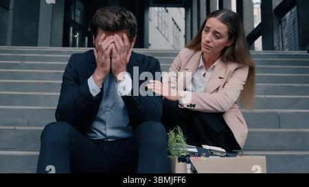 Caucasian stressed male man guy with box sitting on stairs of office businessman dismissed from work business dismiss unemployment woman female girl Stock Photo