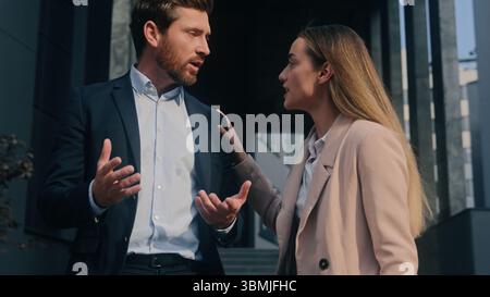 Two Caucasian business colleagues arguing talking conflict quarrel in city outdoor work problem discuss angry irritated stress man businessman guy Stock Photo