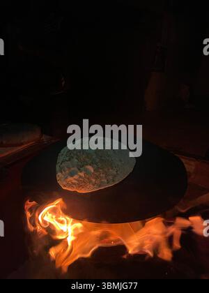 Making Saj bread on a traditional iron plate with firewood. Stock Photo