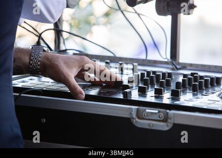 Dj adjusting controls on a mixing console during a music event Stock Photo