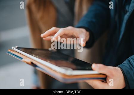 Closeup of hands interacting with a tablet device during an outdoor meeting Stock Photo