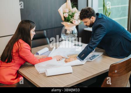 Business professionals discussing architectural plans in a modern office environment Stock Photo