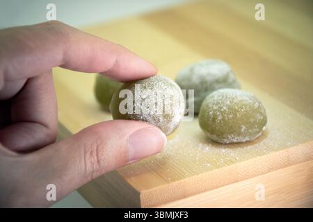 Hand holding traditional green Japanese sweet rice cake mochi Stock Photo