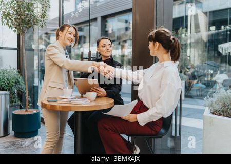 Businesswomen having a meeting in a modern cafe while discussing a collaborative project. Stock Photo