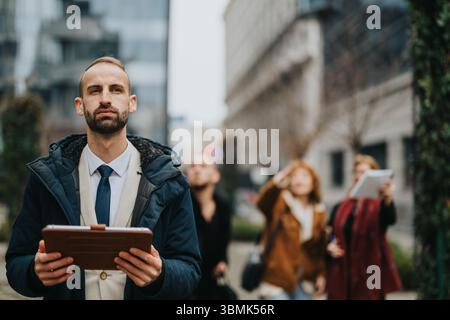 Professional Looking Away Outdoors in Urban Setting Holding Tablet Stock Photo