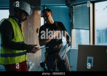 Construction professionals collaborating on a renovation project inside a modern office building Stock Photo