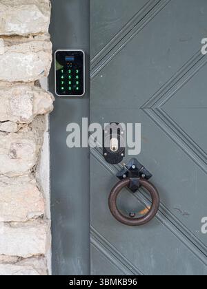 Modern electronic keypad lock and vintage door knocker on historic stone building, concept of security and technology, Estonia. Stock Photo