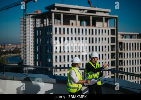 Architects discussing building plans at a construction site Stock Photo