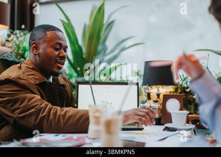 Two Multiracial Professionals Collaborating in a Cafe and Discussing Strategy Stock Photo