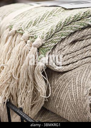 A green and white blanket with fringes is placed over another blanket. Stock Photo