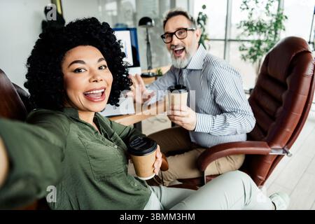 Cheerful colleagues enjoying coffee while collaborating in a stylish office setting showcasing enthusiasm and teamwork Stock Photo
