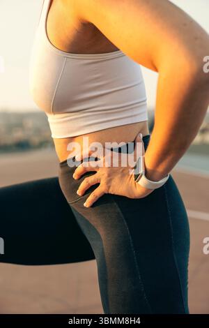 Side view close-up of a fit woman performing a lunge. Focus on proper form for leg and glute workout. Stock Photo