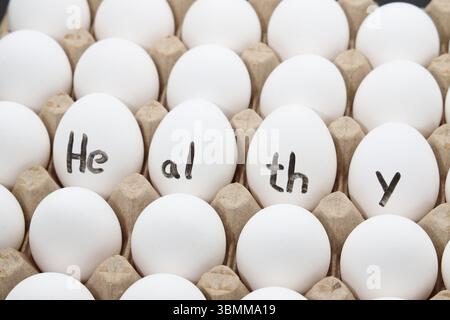 white chicken eggs in the cardboard egg tray with a healthy word write on the eggs Stock Photo