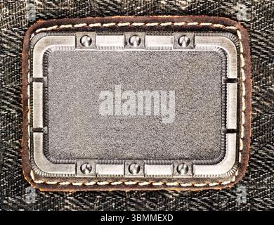 Photo of metal decorative badge or label on denim cloth surface. Stock Photo
