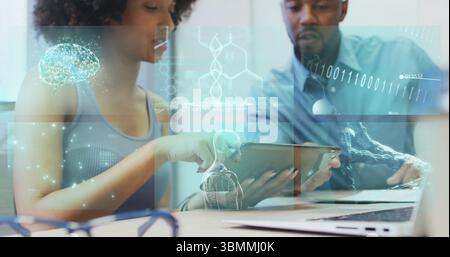 Two researchers collaborating, examining medical holograms on tablet at lab, laptop and eyeglasses Stock Photo