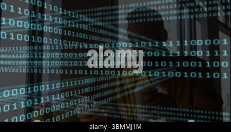 Man wearing fedora holding coffee cup, tapping smartphone in café with binary code on glass panel Stock Photo