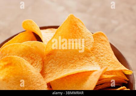 Stacked Golden Potato Chips in Bowl on Beige Background Close-Up Stock Photo