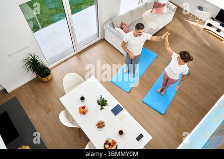 Happy middle aged couple giving high five after workout at home. Top view Stock Photo