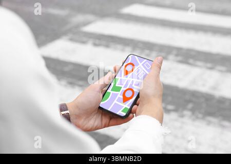 Woman looking at city map on her mobile phone outdoors, closeup Stock Photo