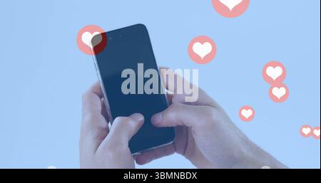 Holding smartphone with image of floating heart icons on blue background Stock Photo