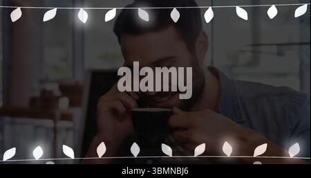 Sipping bearded man wearing denim shirt talking on smartphone at cafe table, with black coffee mug Stock Photo
