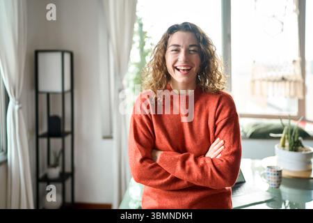 Young smiling pretty lady having fun feeling joyful at home looking at camera. Stock Photo