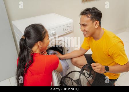 A Joyful Couple Engaging in Doing Laundry Together at Their Cozy Home Environment Stock Photo