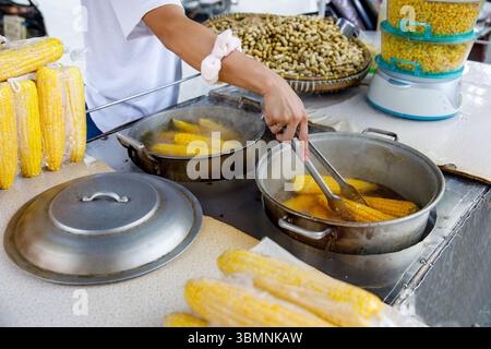Filipino vendor boiling corn on street food stall with peanuts and steamed kernels in background Stock Photo