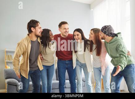 Cheerful friend group meeting, multiethnic team of young people giving common hug, enjoying  Stock Photo