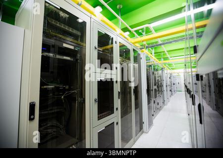 Flat design data center corridor is showing glass-fronted server racks with cables and pipes Stock Photo