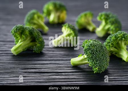 Green organic raw broccoli florets on a dark cuisine table. Stock Photo