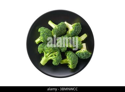 Fresh raw broccoli florets in a black ceramic bowl isolated on white background, top view. Stock Photo