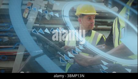 Industrial workers wearing vests and hard hats handling controls in facility, with joystick, AR Stock Photo