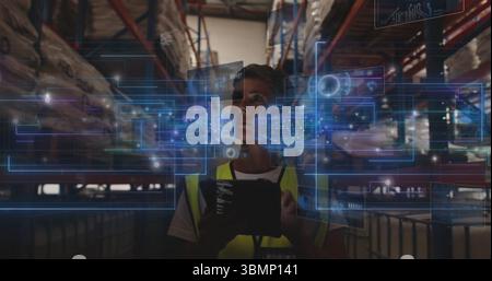 Manager wearing safety vest managing stock using digital tablet in depot, with holographic panels Stock Photo