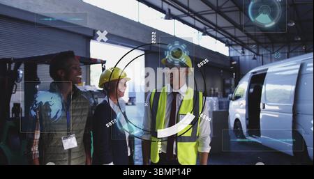 Team in hard hats and vest touring loading bay inside warehouse, with forklift and pallets Stock Photo